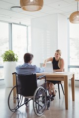 Smiling executives shaking hands at desk