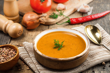 Bowl of delicious lentil soup with bread on an old wooden table. Traditional healthy vegetarian food. Close-up shot.