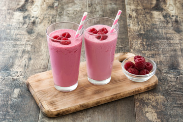 Raspberry smoothie in glass on wooden table
