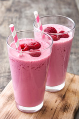 Raspberry smoothie in glass on wooden table
