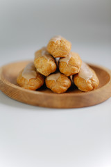 Eclairs on white background on wooden plate