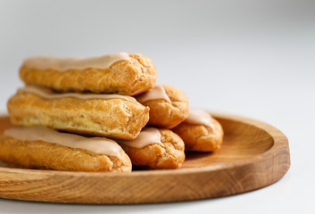 Eclairs on white background on wooden plate