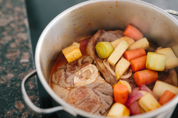 Cooking shanks with vegetables in pot