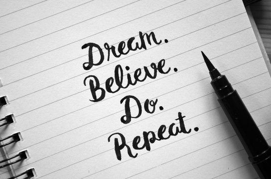 DREAM. BELIEVE. DO. REPEAT. motivational quote written in notebook