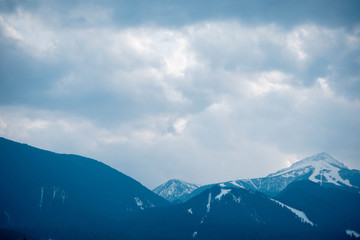 Photo depicting a beautiful moody frosty landscape European alpine mountains with snow peaks on a blue sky background.