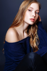 Naklejka premium Fashion portrait of beautiful young woman with blond hair. Girl in a a blue pullover on a black background