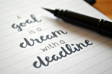A GOAL IS A DREAM WITH A DEADLINE written in notebook on desk