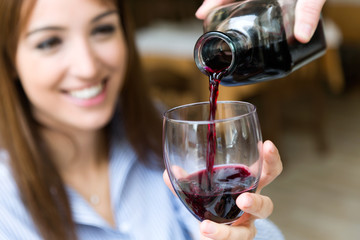 Man serving red wine in the glass of a pretty girl.