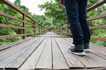 A man on a wooden bridge in the jungle, a long way ahead.