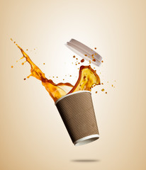 Cup with splashing coffee or tea liquid separated on brown background. Take away hot drink