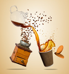 Cup with splashing coffee and grinder separated on brown background. Take away hot drink