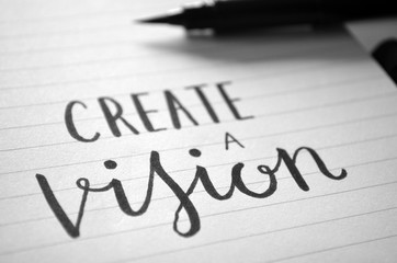 CREATE A VISION handwritten quote in notepad on desk with cup of coffee 