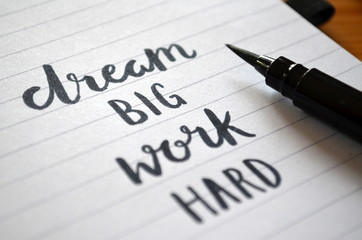 Obraz premium DREAM BIG WORK HARD motivational quote written in notebook
