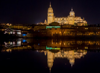 Fototapeta premium View of the cathedral of Salamanca reflected in the river at night, spain