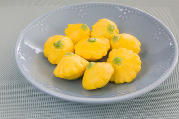 Fresh yellow patissons on a gray plate. Miniature food