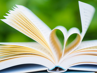 book on table in garden with top one opened and pages forming heart shape