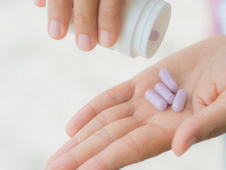 A young woman pours out medicine into her hand