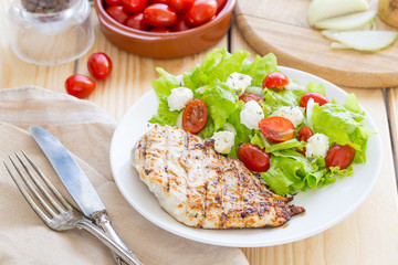 Grilled Healthy Chicken Fillet served with Fresh Salad with Tomatoes and Cheese on a Wooden Background, Horizontal View