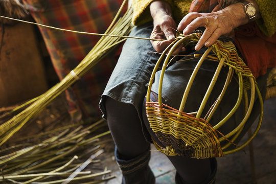 Close up of woman weaving a basket in weaver's workshop.