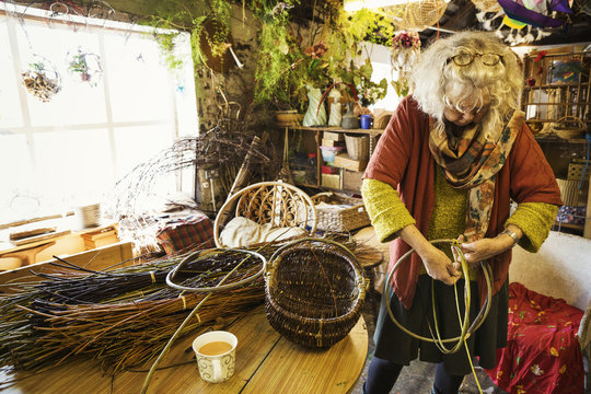 Woman weaving a basket in a weaver's workshop.