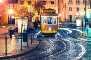 Famous vintage yellow 28 tram of of Alfama, in the oldest district of the Old Town, at night, Lisbon, Portugal - obrazy, fototapety, plakaty