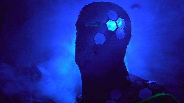 Laser man show. Man in mirror costume in clouds of smoke in darkness.