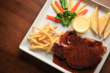 Grilled pork with barbecue sauce and vegetables salad sauce on white dish wooden background