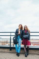Obraz premium couple of women together in cityscape . Two joyful beautiful fashionable girls on roof . Beautiful city view