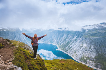 Young woman with backpack standing on fjord coast