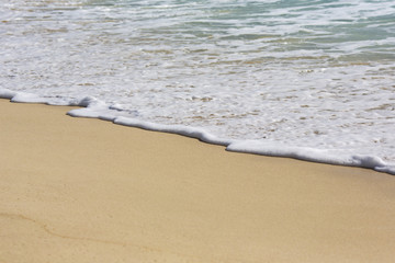 Foamy wave on the sandy beach. Vacation concept image.