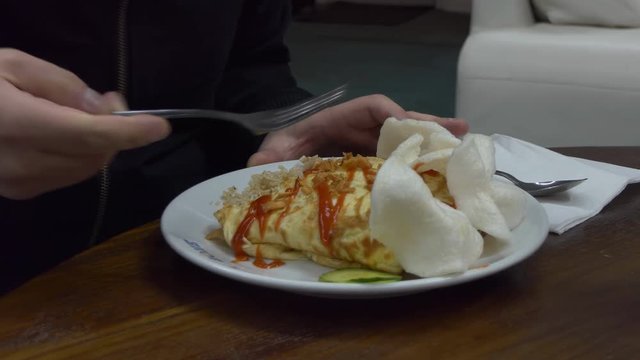 Man having his dinner at Malaysian cafe or restaurant, traditional East Asian meal, Nasi goreng pattaya