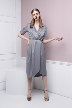 Fashion portrait of young elegant woman in grey dress.