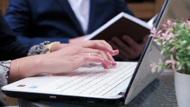 Hands typing on the keyboard in a summer cafe