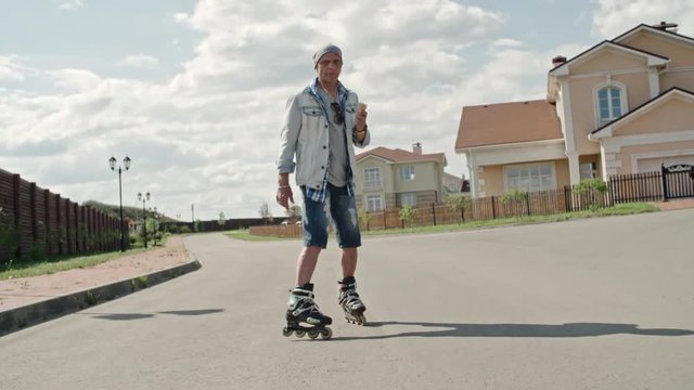 WS Senior hipster on rollerskates eating ice cream cone, stopping on road and looking around