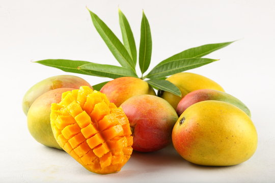 Tropical fresh mangoes with leaves on white background.
