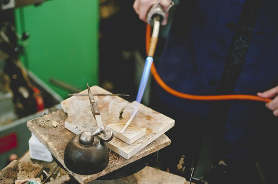 Midsection of senior craftsperson using blowtorch for metalworking in jewelry workshop - Powered by Adobe