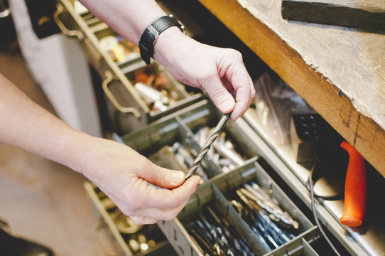Cropped image of senior craftsperson holding drill bit in jewelry workshop