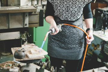 Midsection of senior woman using blowtorch for metalworking in jewelry workshop