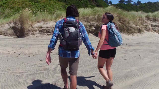 Couple hiking on grassy sand dune trail