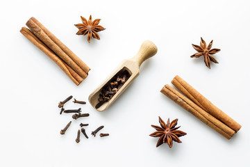 cloves with wooden scoop and cinnamon on white