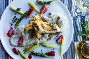 Gourmet restaurant lunch with chicken, asparagus and a glass of white wine.  Top view, white plate on a stripped background. Italian style.