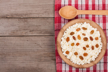 Cottage cheese in a wooden bowl on old wooden background with copy space for your text. Top view