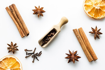 cloves with wooden scoop and cinnamon on white