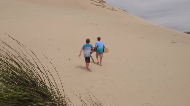 Boys walking with sandboards on dunes, Oregon