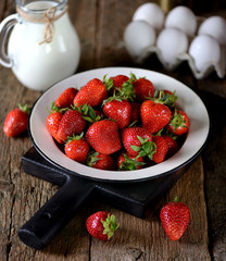 Fresh juicy organic strawberry with milk on an old wooden background. Rustic style.