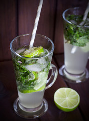 Homemade cocktail with lime and mint on wood background
