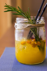 
Cold and fresh sea buckthorn juice with berries and ice in jar. Half empty
