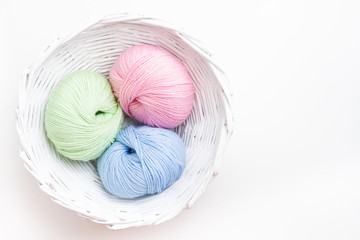 Fototapeta na wymiar Pastel colored yarn in white basket. Copy space.