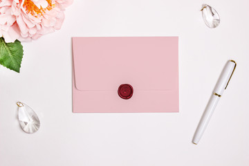 Pink envelope with a rectangular flip, Mockup. Wax seal, pen, flower and wedding decoration.
