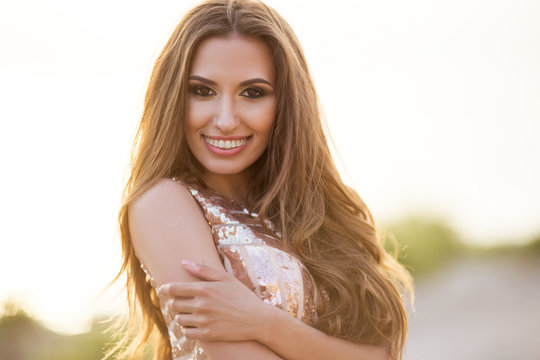 Beautiful tender woman posing on the sunset beach